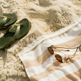 pair of sandals, a towel, and sunglasses on the beach